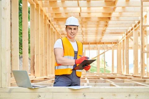 Young architect, builder, engineer standing in wooden building, looking at Stock Photos