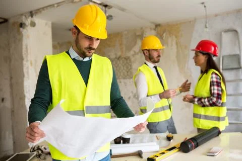 Young architect checking blueprint of  building reconstruction Stock Photos