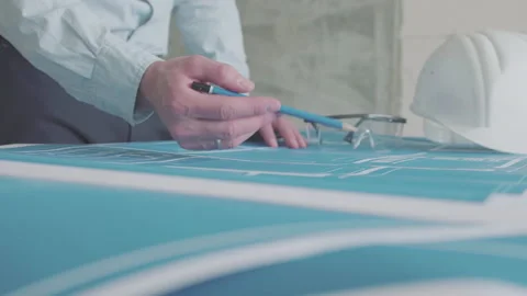 Young architect engineer working with blueprints laid out on a table Video stock 133055772