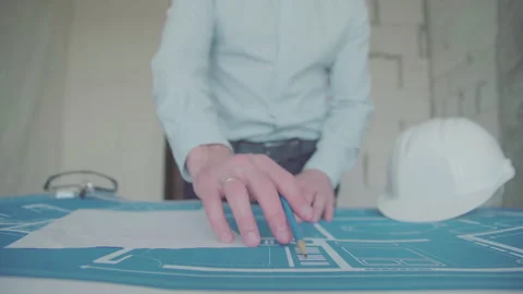 Young architect engineer working with blueprints laid out on a table Video stock 133055893