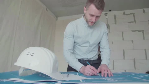 Young architect engineer working with blueprints laid out on a table Video stock 133056572