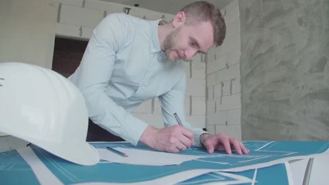 Young architect engineer working with blueprints laid out on a table Video stock 133056648