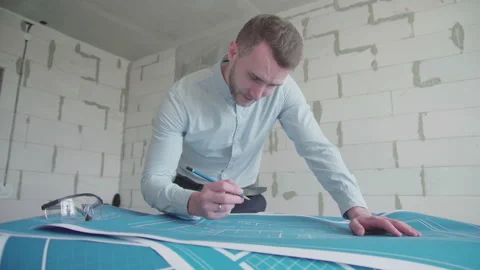 Young architect engineer working with blueprints laid out on a table Video stock 133056701