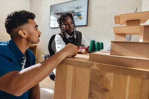 Young architects discussing a model structure in modern workspace Stock Photos