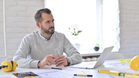 Young Architecture Engineer with Dollars Sitting in Office Stock Photos