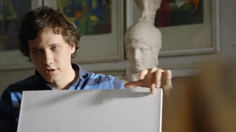 Young art student explains something showing on a canvas Stock Footage 45430106