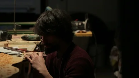 Young artisan draws a wind rose shape out of a board of wood with a fretsaw Stock-Footage 100979493