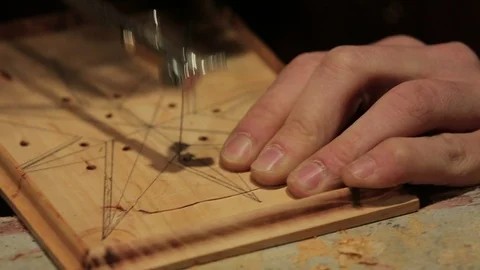 Young artisan draws a wind rose shape out of a board of wood with a fretsaw Stock Footage 100980073