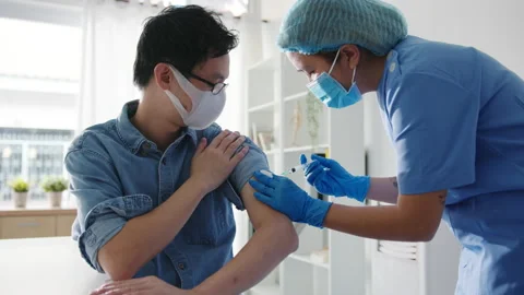 Young Asia lady nurse giving Covid-19 or flu antivirus vaccine shot to patient. Stock Footage