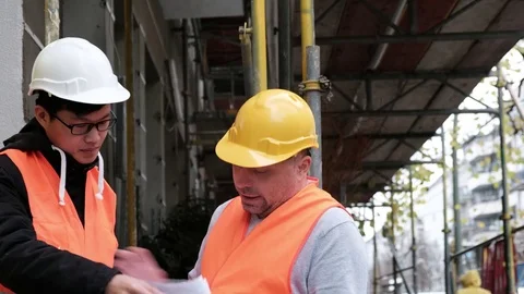 Young Asian apprentice engineer at work on construction site with senior manager Stock Footage 82657155
