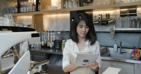 Young asian barista using tablet computer during a break on the work in the Видео 92223908