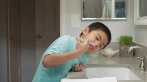 Young asian boy doing sinus nasal irrigation with saline and syringe at home Stock Footage 127996039