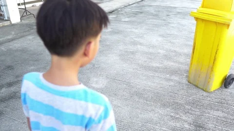 Young Asian boy drop a plastic water bottle in a yellow bin. Stock Footage 92248746