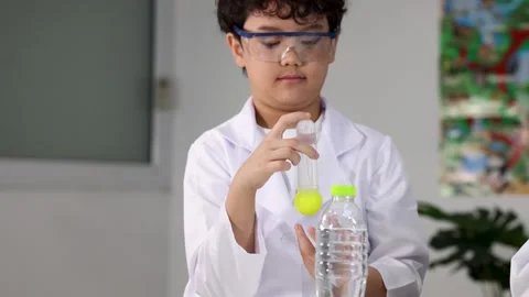Young Asian Boy in Lab Coat Conducting Science Experiment with Test Tube Stock Footage 338437915