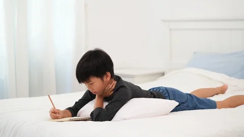 Young Asian boy lay on a bed and get an idea  Stock Footage 127667971
