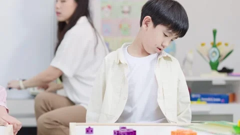 Young Asian Boy Learning with Colorful Building Blocks in Bright Classroom Stock Footage 335617143