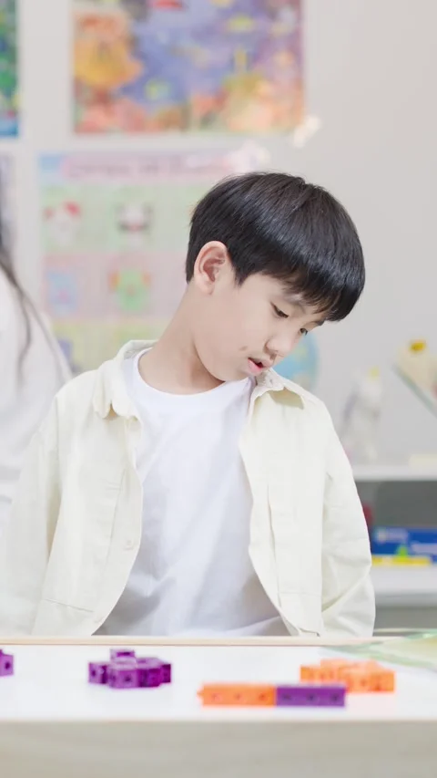 Young Asian Boy Learning Math with Colorful Interlocking Plastic Blocks Stockbeeldmateriaal 345317925