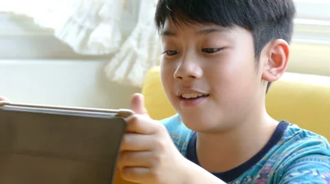 Young asian boy playing games on a touchscreen tablet Stock Footage 62607002