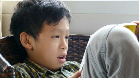 Young asian boy reading a book at home Stock Footage 80911378