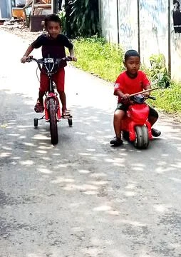 A young Asian boy smiling while riding a red bicycle in Bekasi, may 3, 2026 Foto stock
