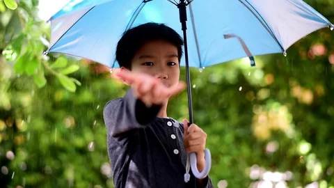 Young Asian boy stand under the rain with umbrella Stock Footage 90507955