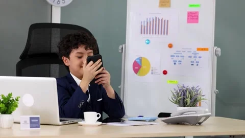Young Asian Boy in Suit Using Smartphone at Office Desk Stockbeeldmateriaal 337086759