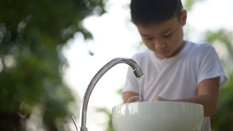 Young asian boy use his hand to take water from new faucet  Stock Footage 76972608