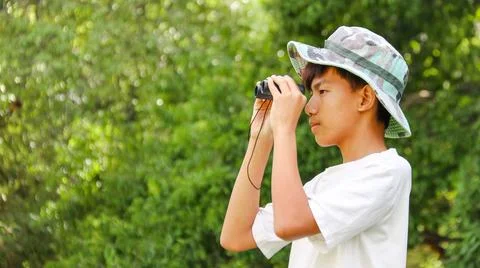 Young Asian boy is using a binocular to lookout for birds and animals Stock Photos