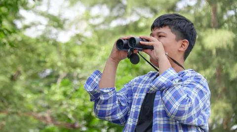 Young Asian boy is using a binocular to lookout for birds and animals Stock Photos