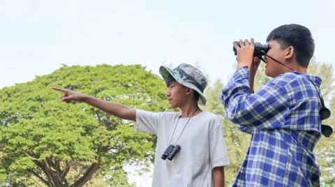 Young Asian boy is using a binocular to lookout for birds and animals Stock Photos