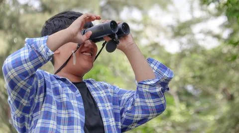 Young Asian boy is using a binocular to lookout for birds and animals Foto stock