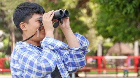 Young Asian boy is using a binocular to lookout for birds and animals Stock Photos