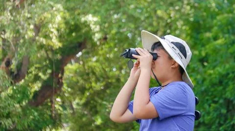 Young Asian boy is using a binocular to lookout for birds and animals Stock Photos