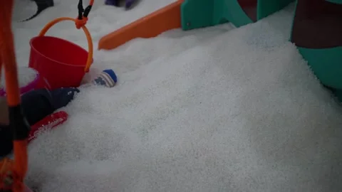 Young asian boy using a colorful shovel and bucket, playing with white sand Stock Footage 296889328