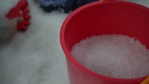 Young asian boy using a colorful shovel and bucket, playing with white sand Stock Footage 296891284