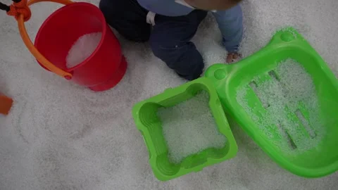 Young asian boy using a colorful shovel and bucket, playing with white sand Stock Footage 296891446
