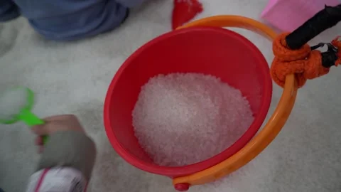Young asian boy using a colorful shovel and bucket, playing with white sand Stock Footage 296893391