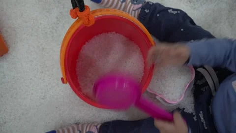 Young asian boy using a colorful shovel and bucket, playing with white sand Stock Footage 296894077