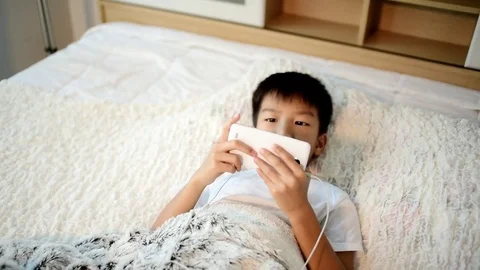 Young asian boy using smartphone on the white bed Stock Footage 81885238