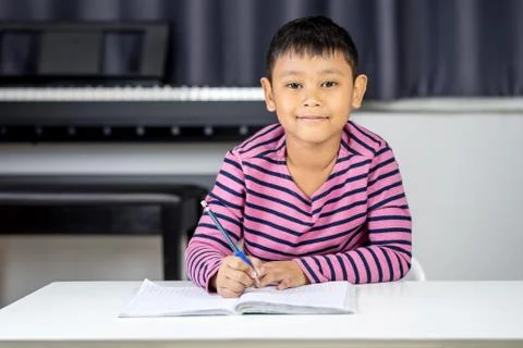 Young Asian boy write on the note book by pencil in the room Stock Photos