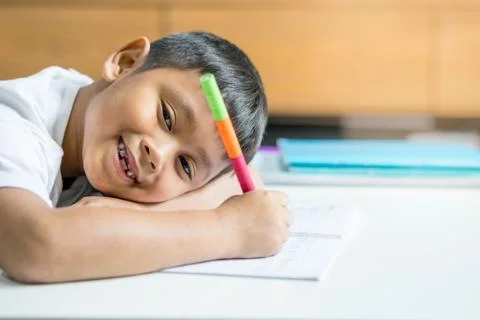 Young Asian boy write on the note book by pencil in the room Stock Photos
