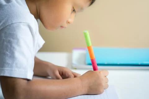 Young Asian boy write on the note book by pencil in the room Stock Photos