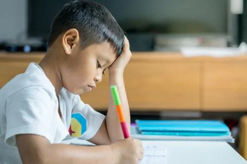 Young Asian boy write on the note book by pencil in the room Stock Photos
