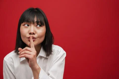 Young asian brunette woman showing silence gesture at camera Stock Photos