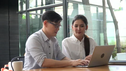 Young Asian business couple  using laptop computer working together in coffee Stock Footage 158806662
