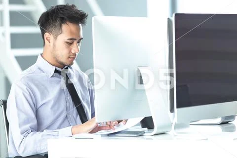 Young Asian businessman in a casual is sitting concentrate and intently to wo Stock Photos