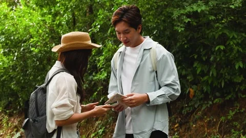 Young Asian Couple Checking Paper Map While Hiking on Forest Trail Stock Footage 345784549