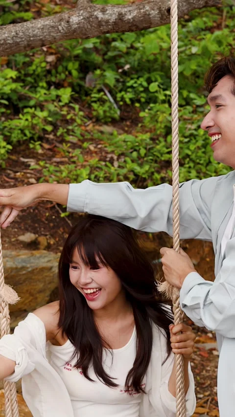 Young Asian Couple Having Fun on a Rope Swing Outdoors Stock Footage 346219895