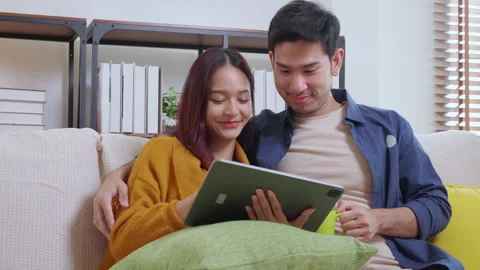 Young asian couple looking on tablet for relax with cozy and contentment si.. Vidéo 303219945