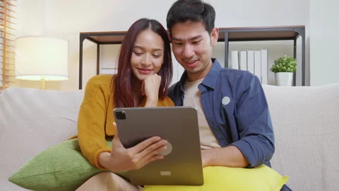Young asian couple looking on tablet for relax with cozy and contentment si.. Vidéo 303219963